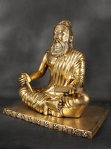 Brass Valmiki sculpture seated, draped robe with ridged folds, holding book and open hand