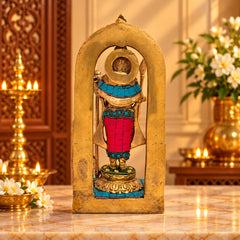 Brass divine child idol statue in arched frame, teal and red jeweled clothing.