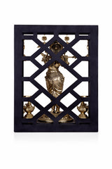 Brass Lord Krishna figurine on dark lattice panel with bells and lamp holders