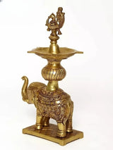 Brass oil lamp on elephant base with peacock finial, ornate engraving