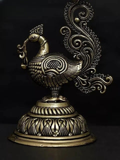 Brass peacock diya statue, side view with ornate feather-like handle and bowl