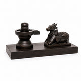 Dark Shiva lingam and seated Nandi statue on rectangular wooden stand