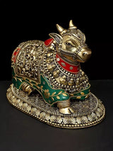Ornate brass Nandi figurine, red saddle markings, green accents, front-left view
