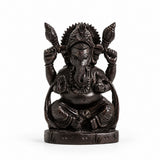 Black seated Lord Ganesha statue with detailed trunk, crown, four hands, and carved pedestal
