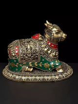 Brass Nandi idol with engraved patterns, red ornaments, green base trim, side view