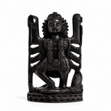 Dark carved Kali deity idol figurine with raised arms and crown, seated on base