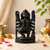 Dark carved deity idol figurine with multiple arms, seated on patterned base