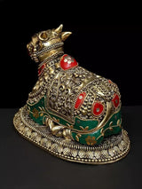 Brass Nandi figure with detailed engraving, red medallions and green inlay, angled view