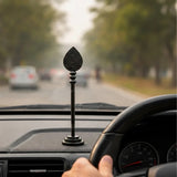 Small dark wooden vel on car dashboard with engraved lotus teardrop top