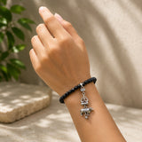 Black bead bracelet on wrist with silver-tone Shiva trident and Nandi charm