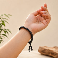 Black wooden bead bracelet on wrist with tassel ends and round bead strands