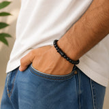 Black bead mala bracelet on wrist; damru pendant not visible