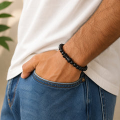 Black bead mala bracelet on wrist; damru pendant not visible