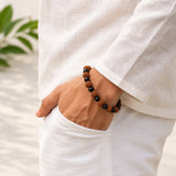 Rudraksha bead bracelet on wrist with dark matte and textured orange-brown beads