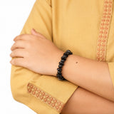 Black wooden beaded spiritual bracelet on wrist with tan sleeve