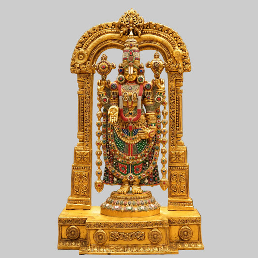 Front view of ornate brass deity idol on decorated pedestal with colorful ornaments