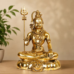 Brass Shiva statue seated with trident staff, glossy gold finish, lotus base and garlands.