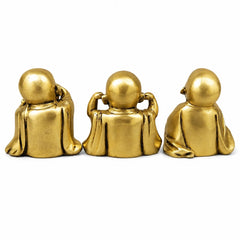 Brass seated monk sculpture trio, back view with rounded bald heads and robes