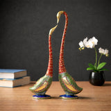 Kissing swan couple statues, red-and-gold curved necks, green mosaic bodies, blue bases