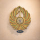 Brass peacock wall hanging with gem-studded fan and bell center, AONA logo