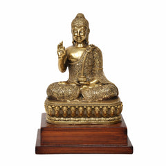 Brass Buddha statue seated in Abhaya mudra, detailed robe and golden finish