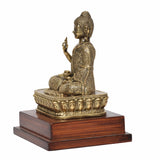 Side view brass Buddha statue in Abhaya mudra, seated on patterned golden base
