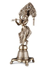 Brass Krishna idol side view with decorative arch, raised hand, detailed patterned attire