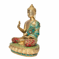 Brass Buddha idol side view, gold face and torso, turquoise and red inlaid seated robe