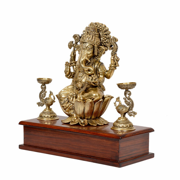 Side view of brass Lord Ganesha idol on wooden base with lamp holders