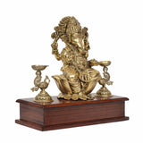 Brass Lord Ganesha idol on wooden base from back angle, with lamp holders