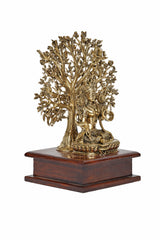 Brass Tara Devi statue on dark wooden two-tier base with tree canopy, side view