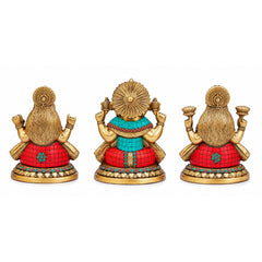 Three brass Ganesha, Lakshmi, Saraswati idols with red patterned garments, back view