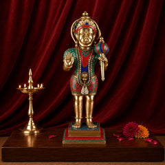 Brass Hanumanji statue with painted ornaments and colorful garland, standing on base