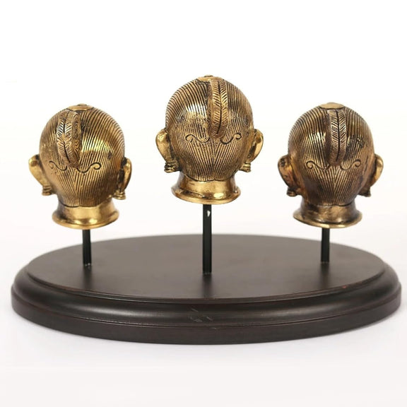 Brass head idols rear views on round dark base, three figures