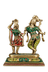 Radha and Krishna dancing brass sculpture, viewed from behind with green and red decor