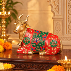 Brass Nandi bull idol with red and green jeweled patterns, reclining side view