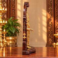 Side view of brass Balaji idol statue inside wooden mandir with hanging diya lamp