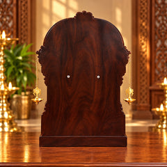 Carved dark wooden mandir back panel with hanging diya lamp chains
