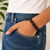 Black carved bead bracelet on wrist, round beads with engraved swirl pattern
