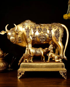 Brass Kamdhenu cow with calf statue, engraved deity figures, raised on ornate base