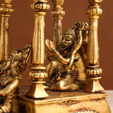 Brass seated deity figure on chariot base with ornate columns and candle-like stands