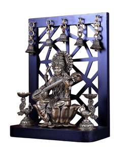 Brass Saraswati idol holding veena, seated on lotus, with lamp stands and bells