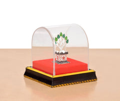 White metal Tulsi plant idol with leafy ornament inside clear dome on black gold base