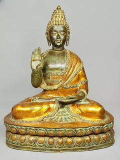 Seated brass Buddha statue with serene face, gilded robe, blessing hand and lap pose