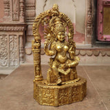 Brass sitting Maa Lakshmi idol with raised hand, ornate headdress and carved base