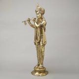 Brass Krishna flute statue in gold finish, standing on round base, side angle