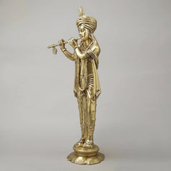 Brass Krishna flute statue in gold finish, standing on round base, side angle