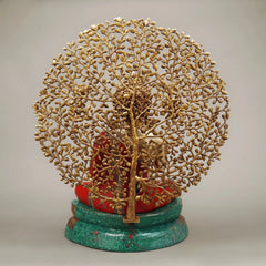 Back view of seated Buddha with tree trunk and branches, red robe, green base, gold-tone details