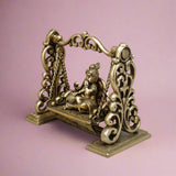 Brass Baby Krishna swing sculpture with curved frame and dangling chains, seated