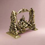 Brass Baby Krishna swing sculpture showing detailed filigree frame and base, seated